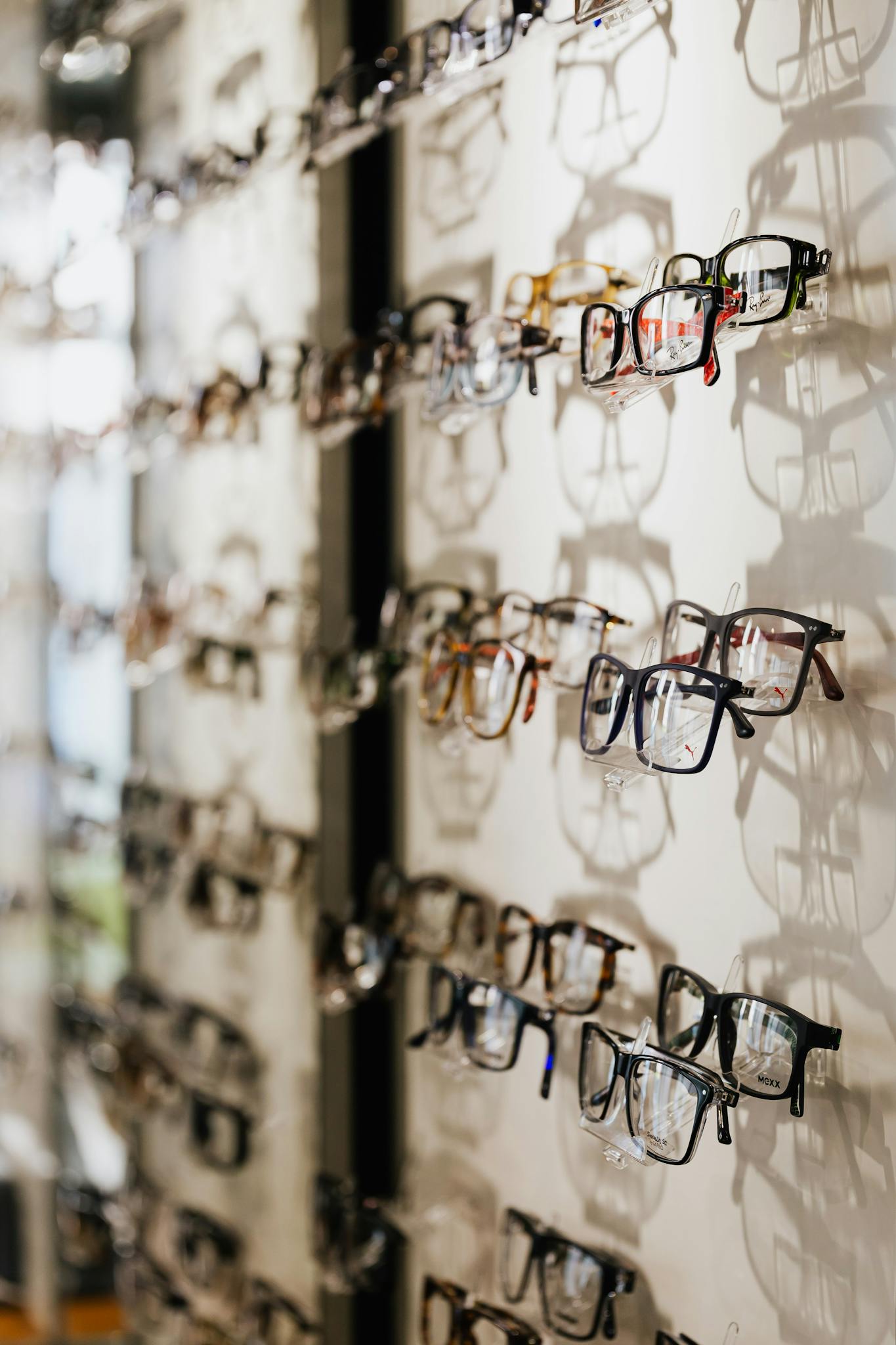 A variety of eyeglasses frames displayed on a wall in an optical store.